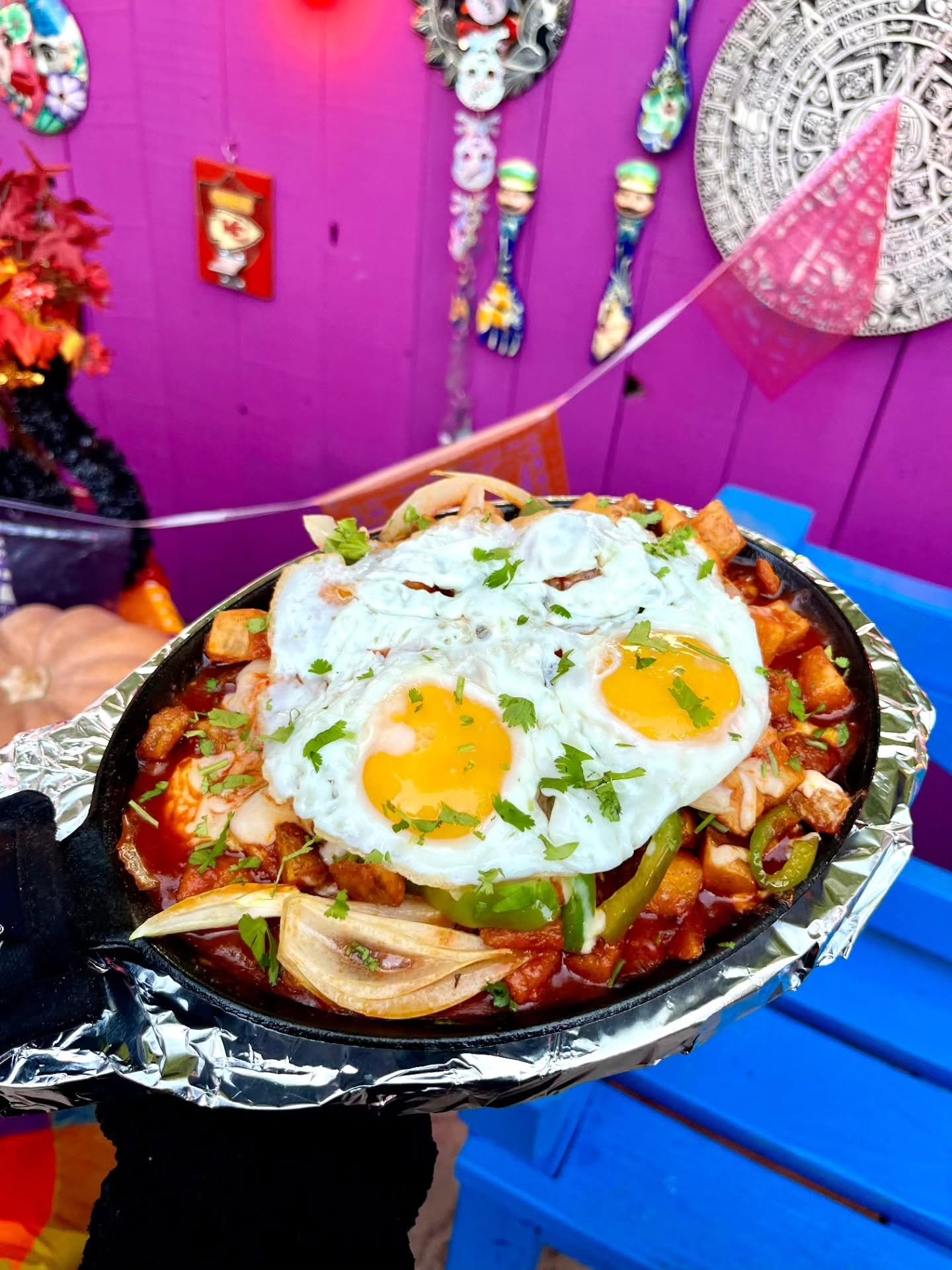Chilaquiles topped with two fried eggs against a purple wall