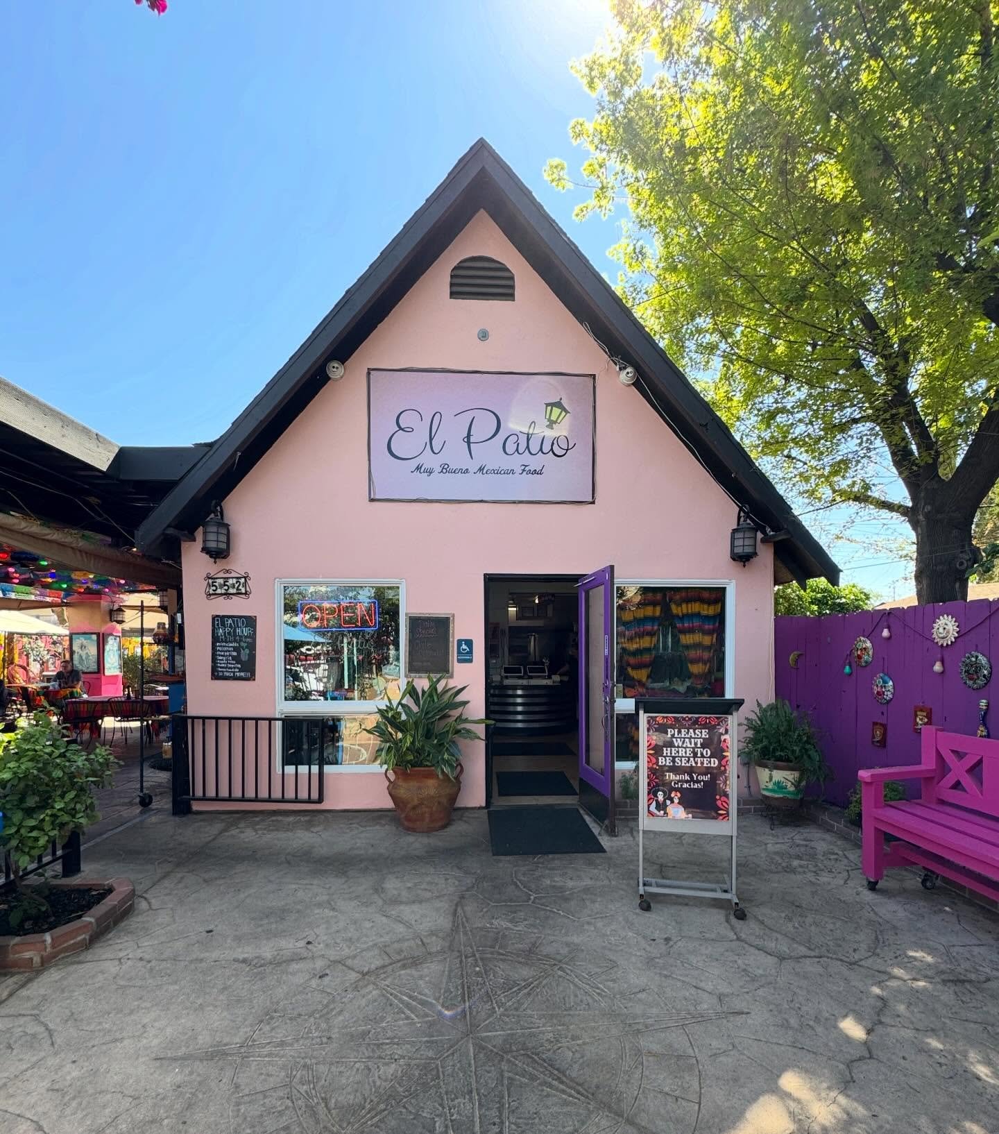 El Patio's pink storefront in Fresno's Tower District, with papel picado, a purple door and a magenta bench